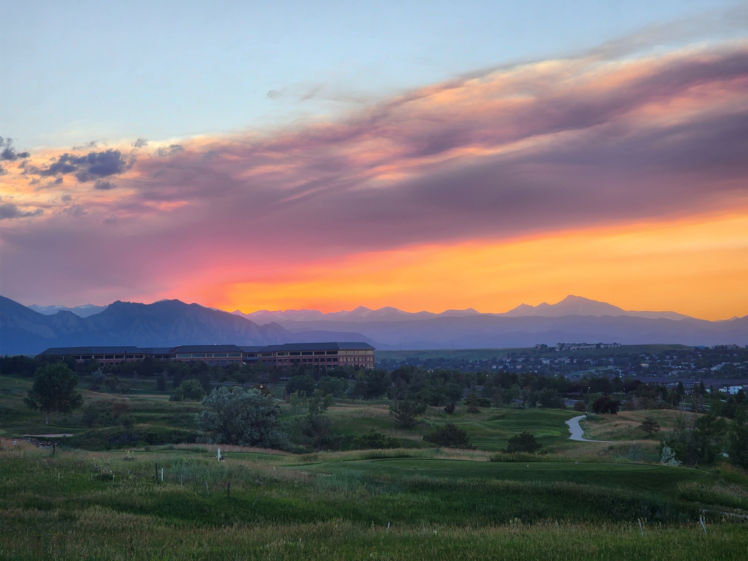 Sunset over the Front Range, with a golf course and rooftops in the middle distance